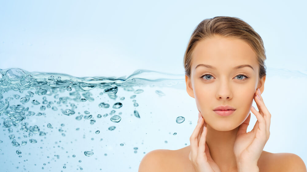 Young woman posing while touching her healthy and smooth facial skin